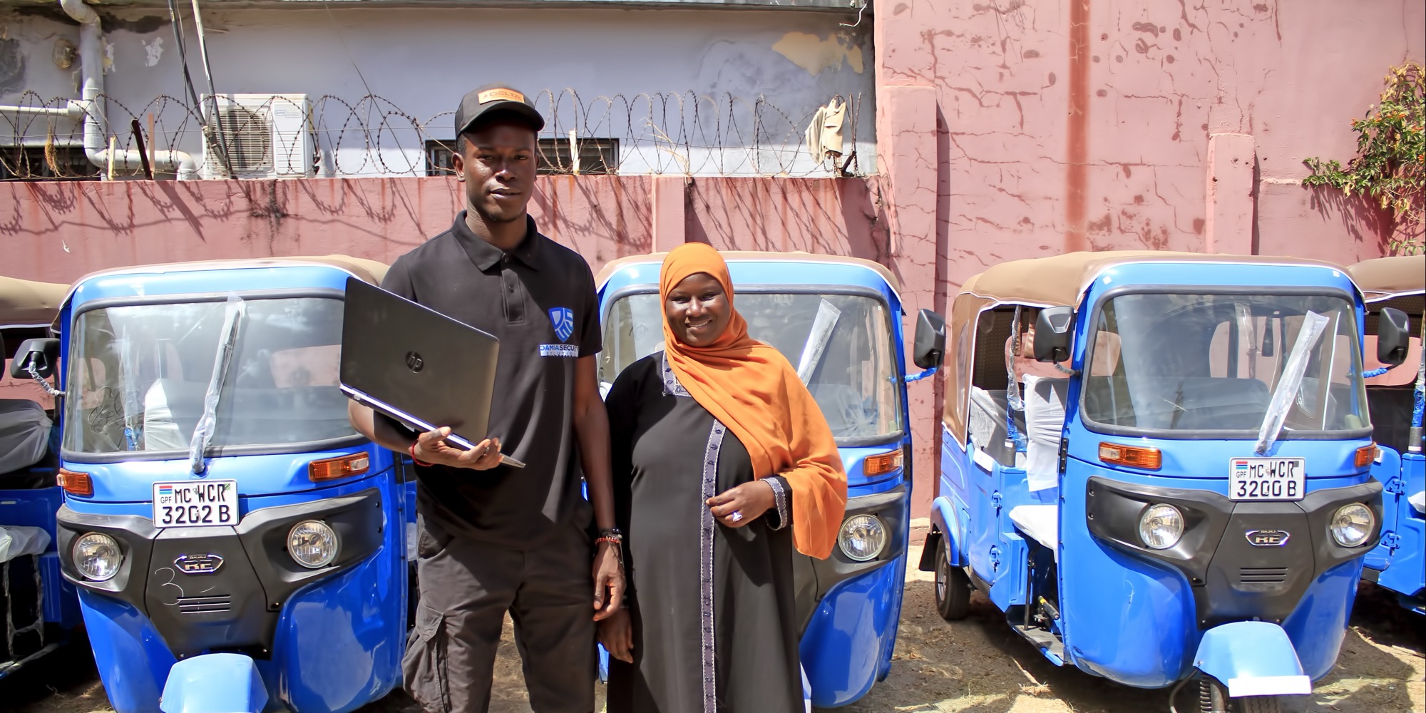 Damia Tracker technician with a customer in front of new blue tricycle taxis