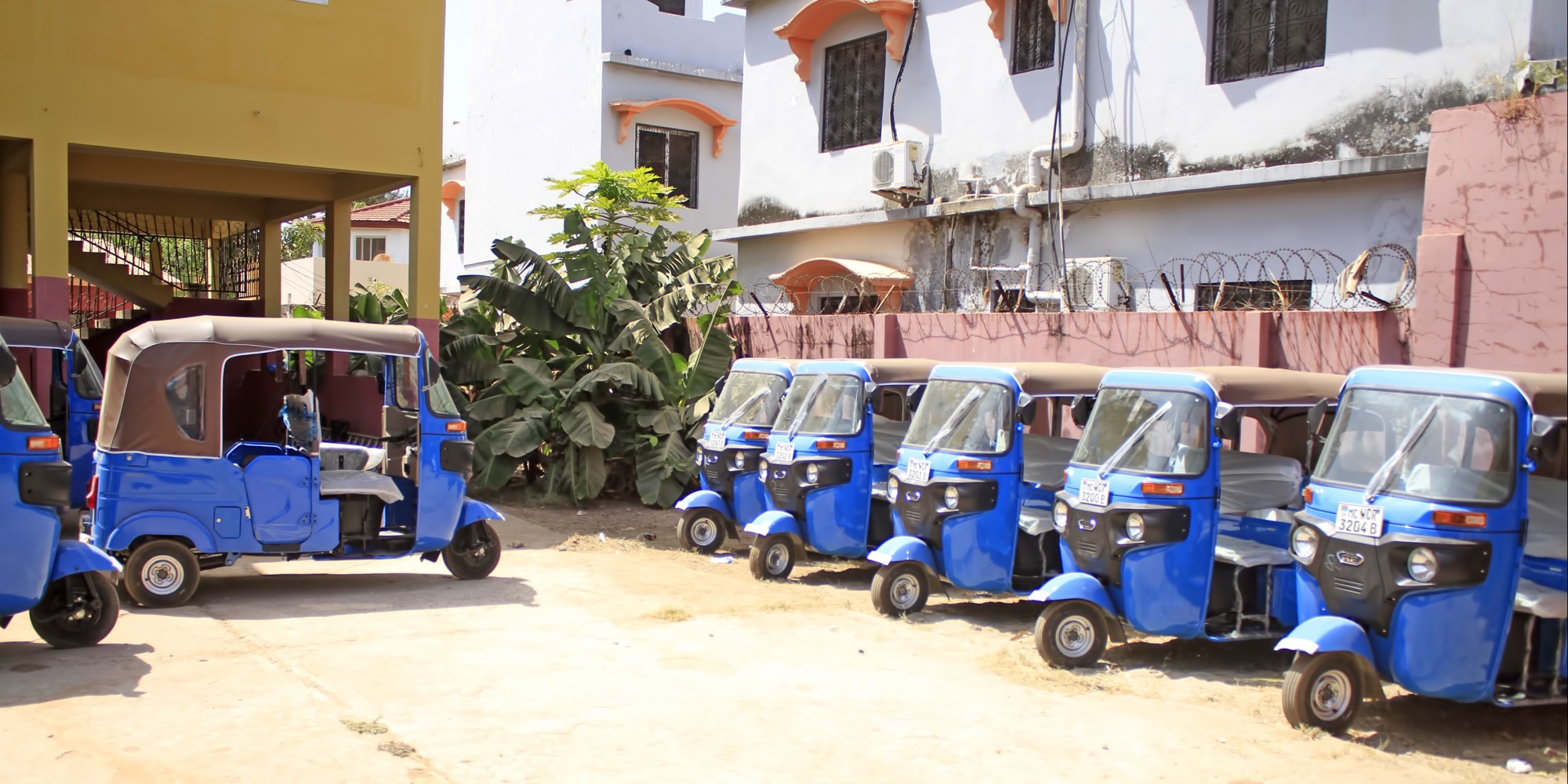 A row of blue tricycle taxis fitted with trackers