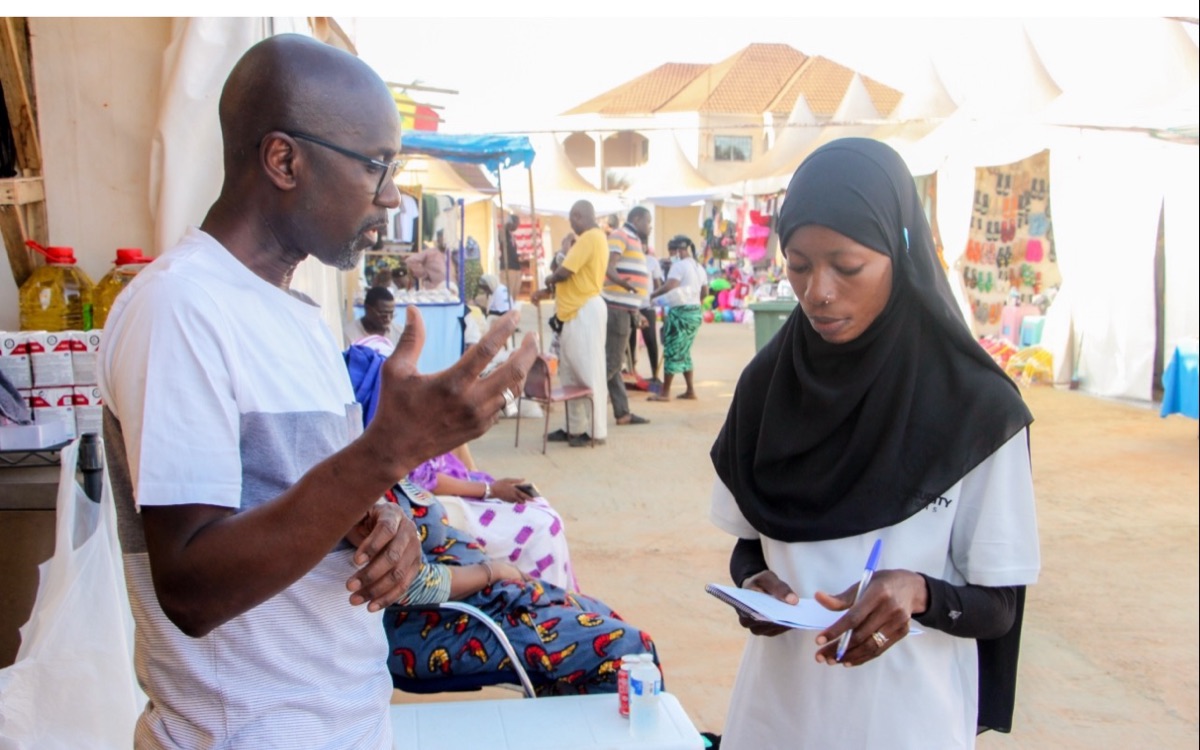 A Damia Tracker agent taking a customer's details at a market stall